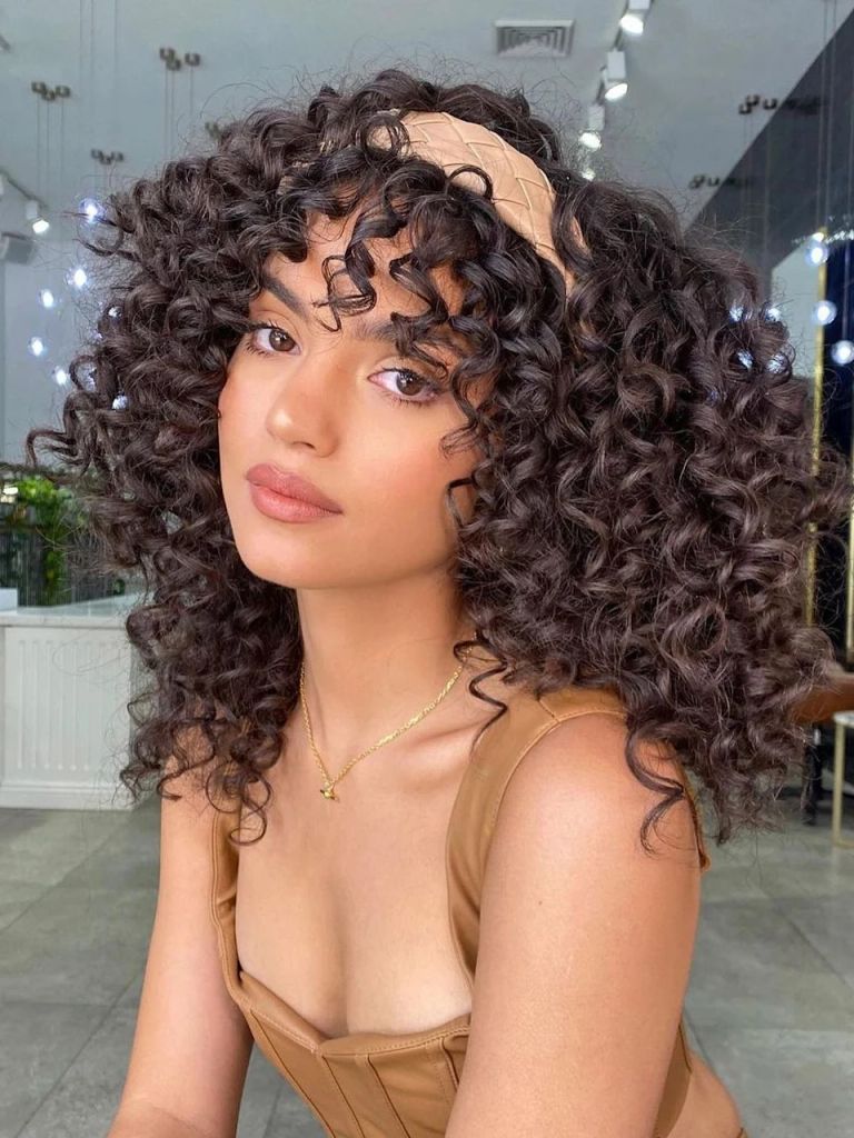 @natalieannehair poses with her curly hair and a headband 