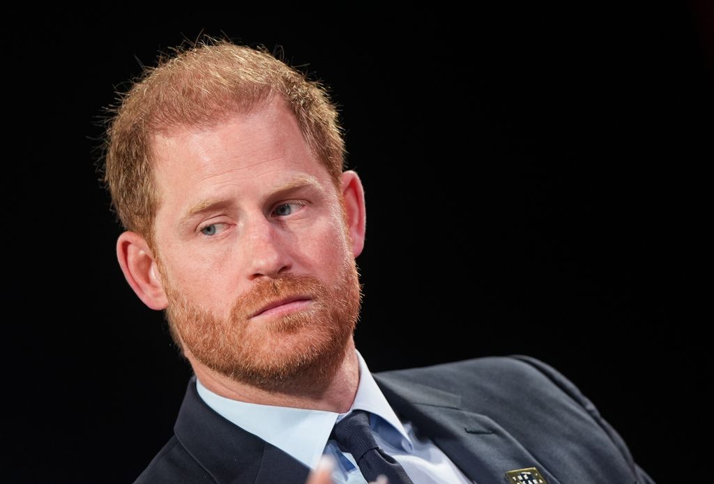 Prince Harry in a grey suit against a black background