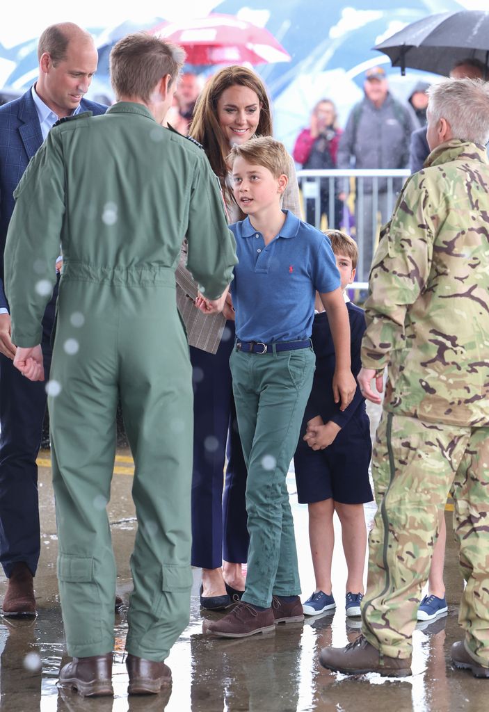 kate and prince george shaking hand with man in military camouflage in rain